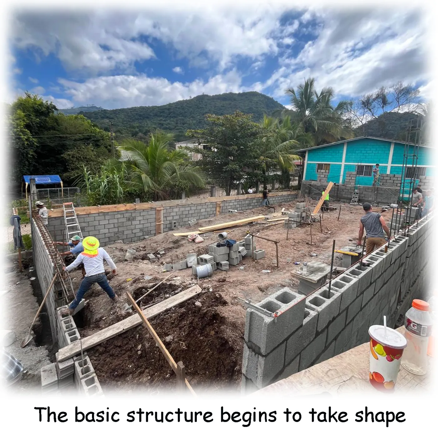 A health clinic under construction in Honduras, with workers raising walls.